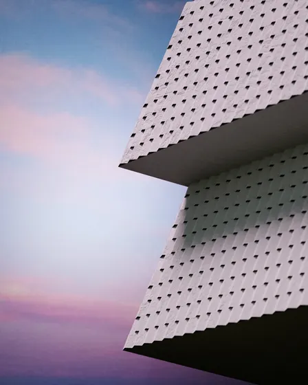 Geometric white building silhouetted against a pink-blue sky