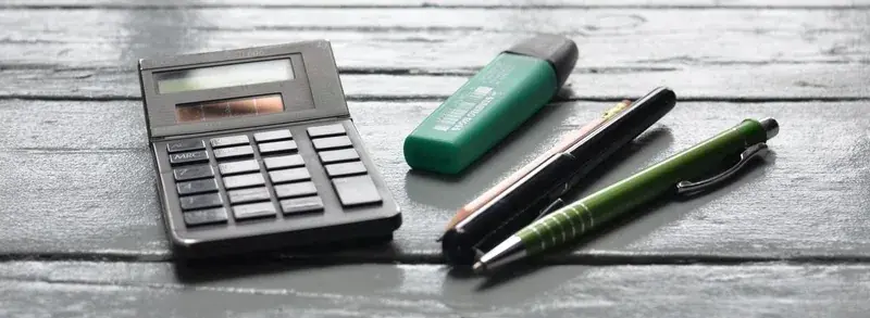 Calculator and pens on a wooden desk