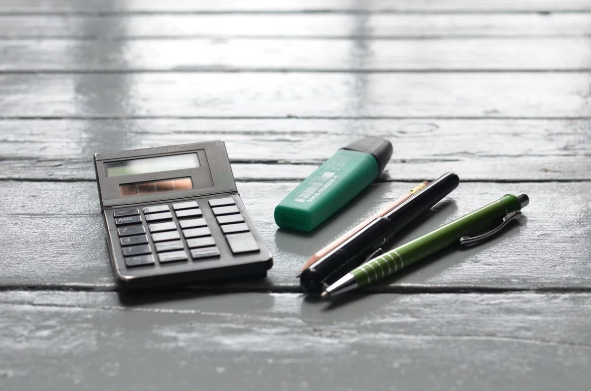 Calculator and pens on a wooden desk